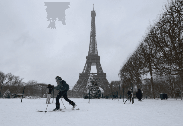 Mulher nos campos cobertos de neve perto da Torre Eiffel, em Paris  | Reprodução/Reuters