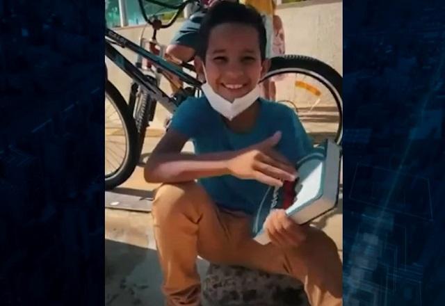 Nicolas Gabriel, sentado na calçada, lendo a bíblia. Garoto vendia balas em semáforo de Goiânia (GO)