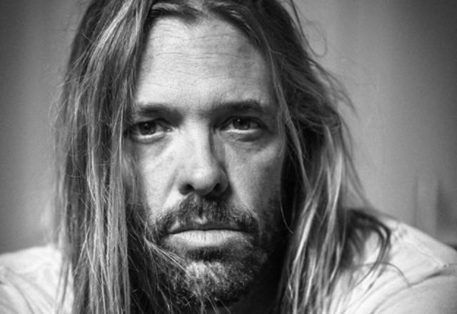 O baterista Taylor Hawkins; ele é branco, e tem o cabelo longo. Foto está em preto e branco
