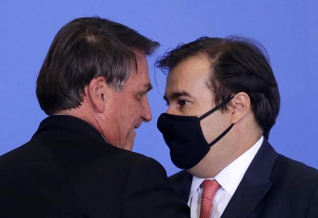 O presidente da República, Jair Bolsonaro, em frente a Rodrigo Maia, de máscara