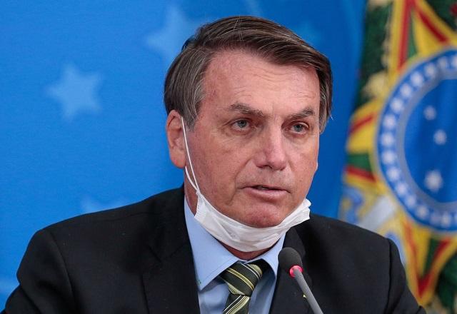Com máscara posicionada abaixo do queixo, Bolsonaro fala ao microfone (Carolina Antunes/PR)
