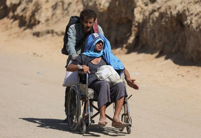 Palestino ajuda homem em cadeira de rodas depois que forças israelenses ordenaram que residentes da Cidade de Gaza saíssem em direção ao sul | 2/10/2025/Reuters/Dawoud Abu Alkas