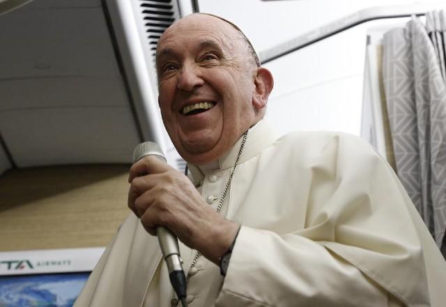 Papa sorri e segura microfone em cabine de avião