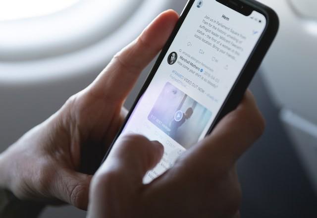 Pessoa com celular na mão mexendo em rede social