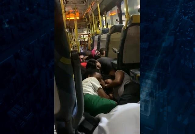 Pessoas agachadas e deitadas dentro de ônibus