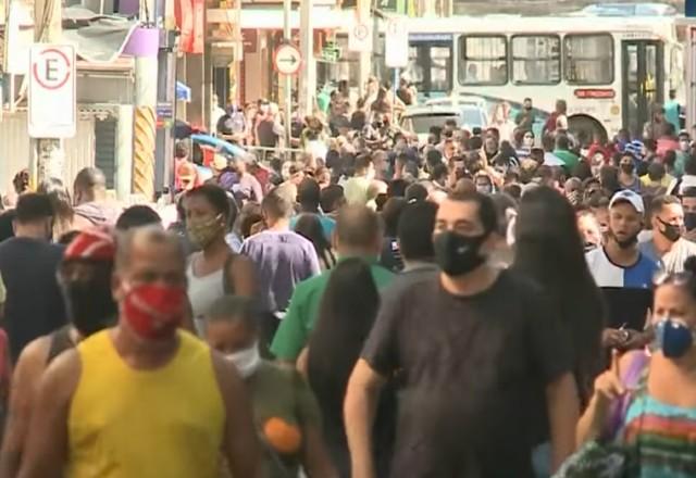 Pessoas andam com máscaras na rua
