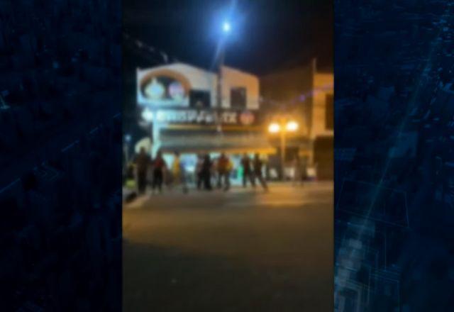 Pessoas brigando em frente a estabelecimento durante a noite
