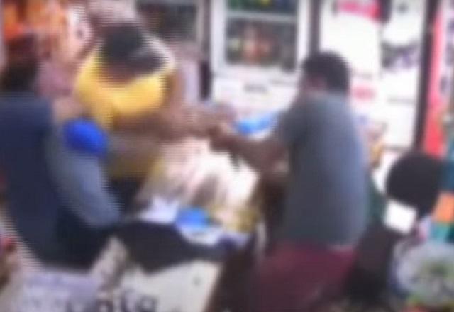Pessoas em luta corporal durante tentativa de assalto dentro de mercado, com caixa desarmando homem armado