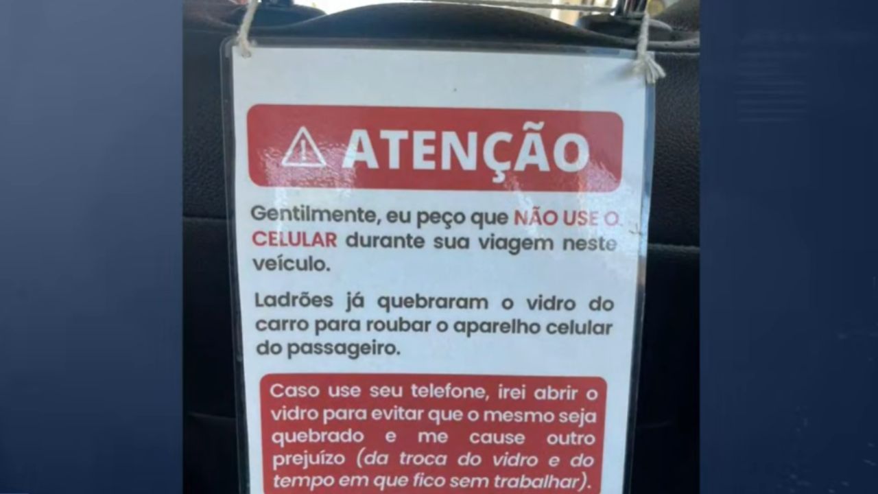 Taxista coloca placa proibindo uso de celular em viagens Taxista coloca placa proibindo uso de celular em viagens