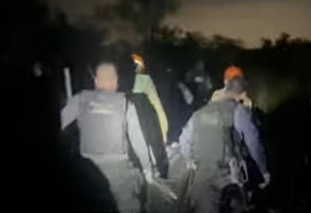 Policiais carregando corpo em um saco preto