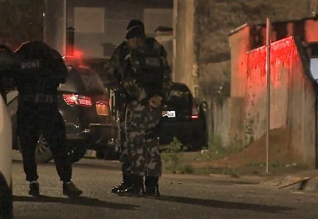 Policiais fardados em rua, durante a noite, em cena de crime