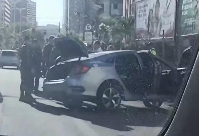 Policiais fardados reunidos ao lado de carro que sofreu colisão