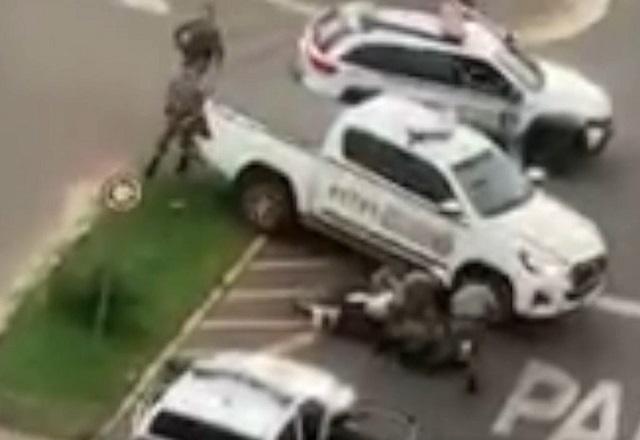 Policiais rendem motociclista, com moto caída no asfalto e viaturas da brigada militar no meio da rua