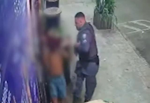 Policial militar fardado chutando homem em frente a loja, na calçada