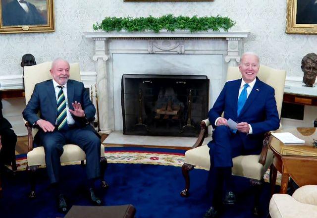 Presidente Lula acena com a mão enquanto presidente Joe Biden sorri, ambos no Salão Oval da Casa Branca