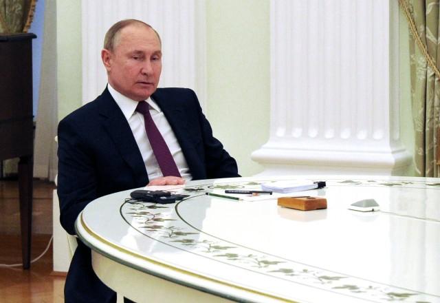 Putin sentado em encontro com chanceler alemão