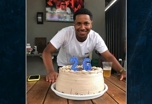 Rapaz negro em frente a bolo de aniversário, com velas com os números dois e seis