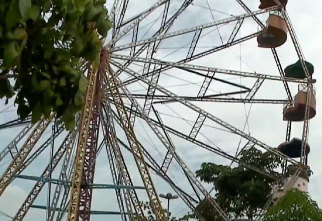 Roda gigante aparece rodeada por árvores em parque de diversões (SBT Jornalismo)