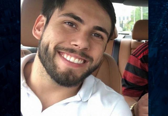 Rosto de homem branco, de barba, dentro de carro e sorrindo