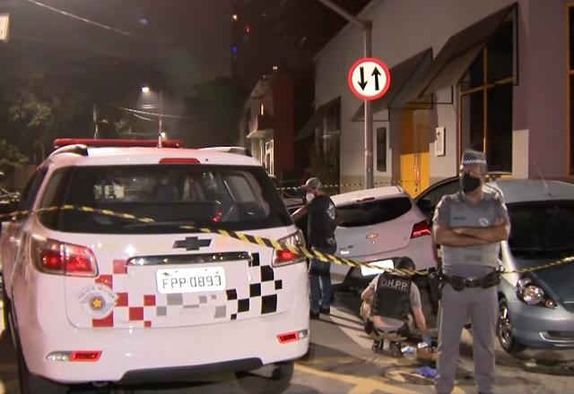 Ao lado de viatura, policial militar cerca área (Reprodução/SBT Brasil)