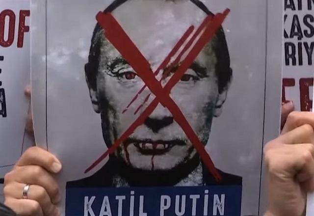 Manifestante segura cartaz com um 'x' em vermelho no rosto de Vladimir Putin (Reprodução/SBT Brasil)