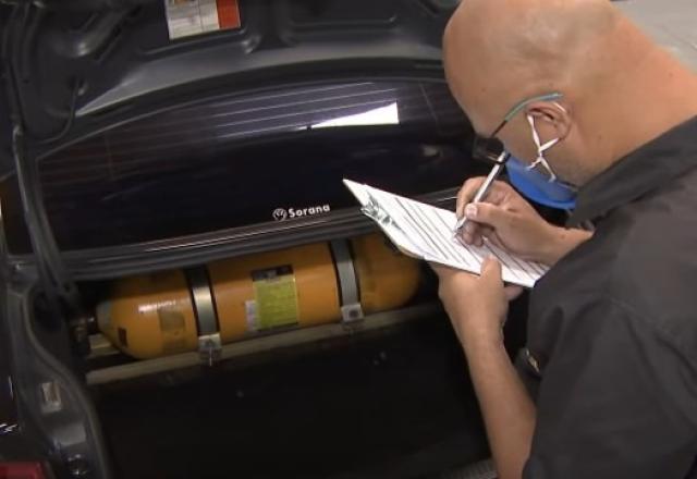 Fiscal faz anotações à frente de cilindro de gás instalado em carro (Reprodução/SBT Brasil)