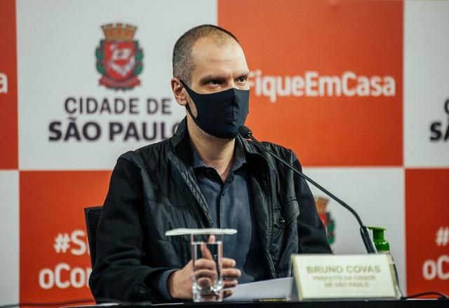 Usando máscara facial, prefeito Bruno Covas fala em microfone durante coletiva de imprensa (Leon Rodrigues/Secom de São Paulo)