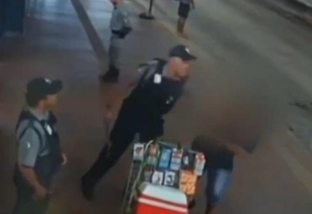 Segurança fardado e armado com cassetete gritando com vendedor ambulante, dentro de terminal de ônibus
