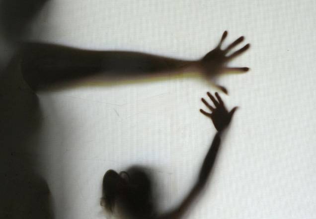 Sombra de um adulto e uma criança em situação de iminente violência