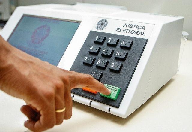 Pessoa se prepara para pressiona tecla Confirma em urna eletrônica (Divulgação/TSE)