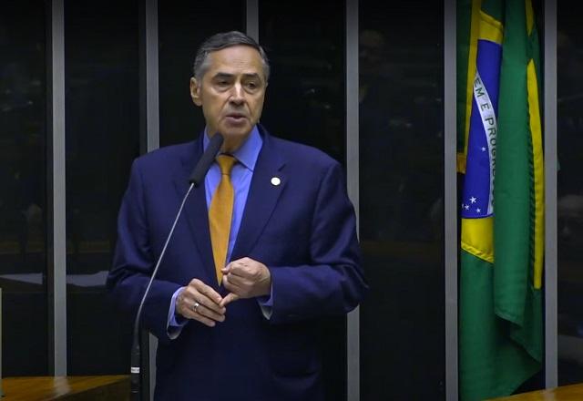 Luís Roberto Barroso discursa, próximo a bandeira do Brasil, em sessão solene na Câmara dos Deputados (Reprodução/TV Senado)