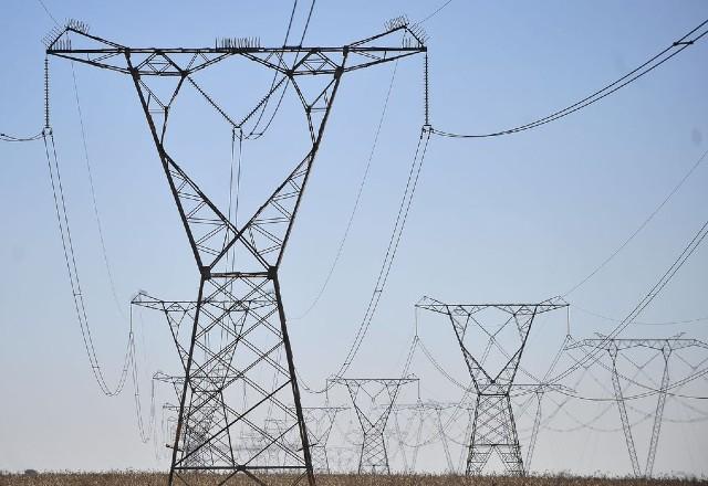 Torres de energia em campo aberto, céu azul