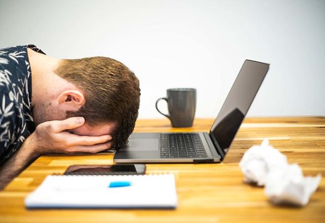 Trabalhador com cabeça baixa em frente a computador