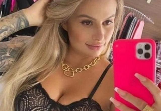 Traficante loira e bonita tirando foto de si mesma com um celular cor de rosa na mão esquerda