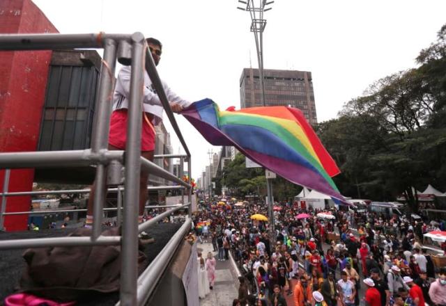 Trio com bandeira do orgulho LGBT em frente ao MASP