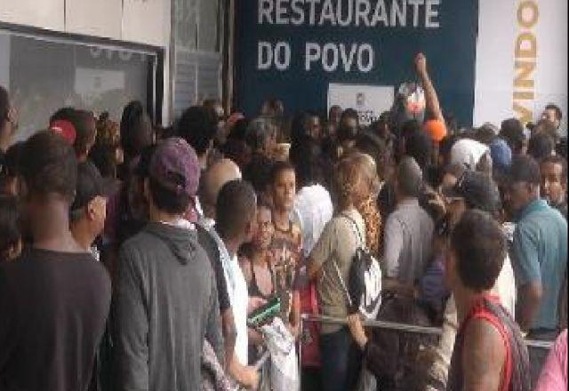 Usuários aglomerados na entrada do restaurante. Ao fundo aparece o nome Restaurante do povo e parta da expressão bem-vindos