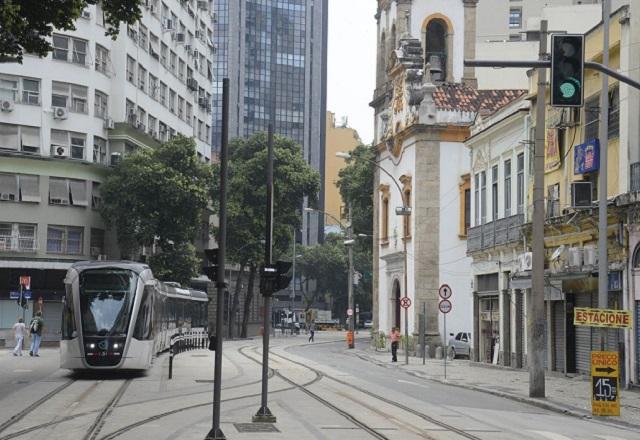 Veículo leve sobre trilhos circulando em via, com prédios ao redor, durante o dia