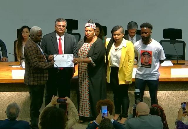 Dino e Sheila de Carvalho entregando certificado à família de Moïse Kabagambe (Reprodução/YouTube)