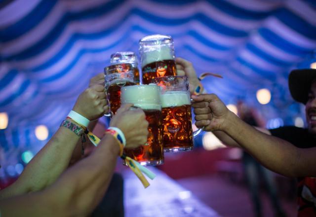 a imagem mostra quatro pessoas brindando com cervejas em um evento