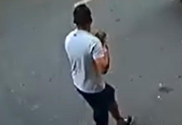 a imagem mostra um dos criminosos com a cachorrinha roubada em seu colo