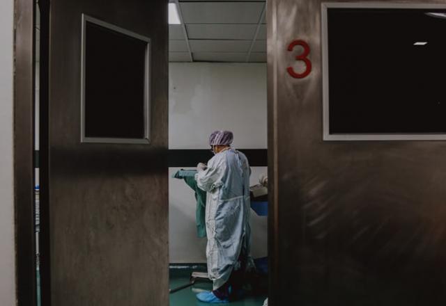 a imagem mostra uma funcionária da saúde tratando um paciente com Covid-19