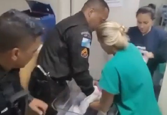 Policial e profissional da saúde colocam bebê resgatado em maca (Reprodução/PM)