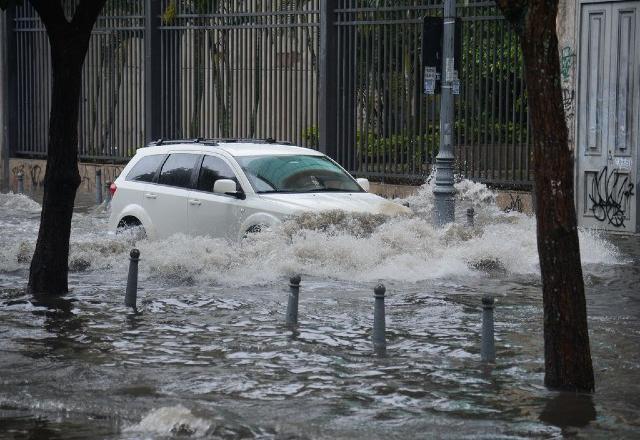 carro branco passando por uma rua alagada