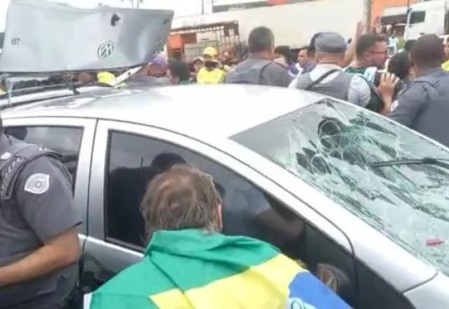 carro sendo destruído por manifestantes