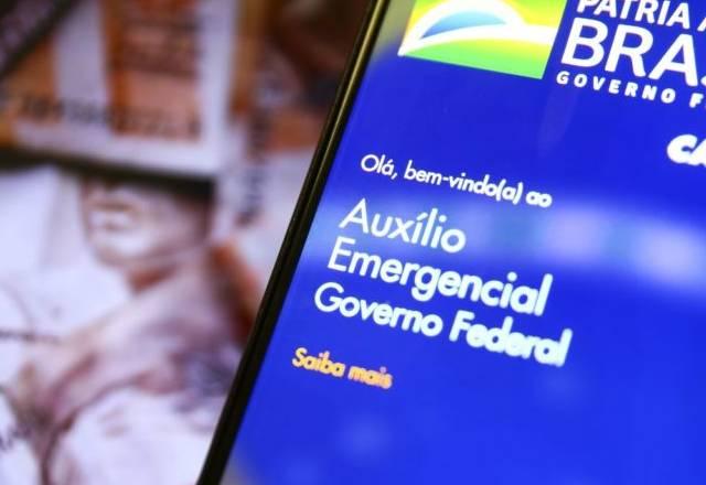 celular com o aplicativo do auxilio emergencial do governo e notas
