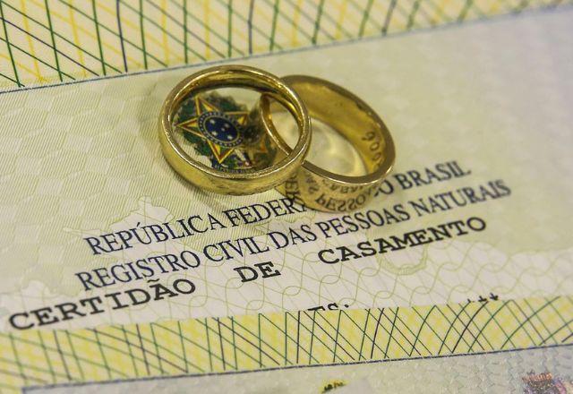 certidão de casamento e duas alianças douradas