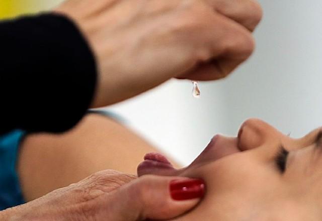 criança toma remédio da polio