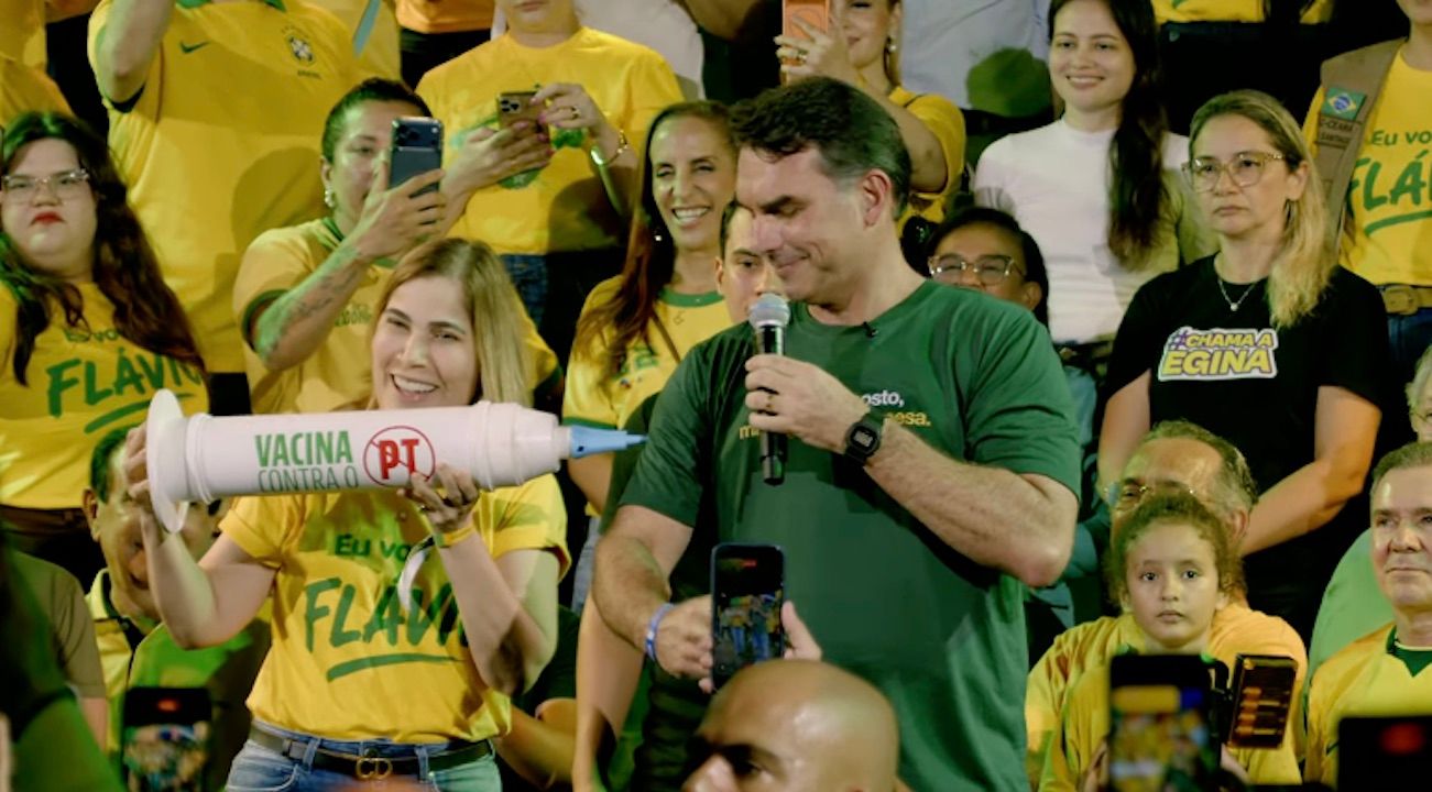 Flávio usa seringa gigante para tomar ‘vacina contra o PT’