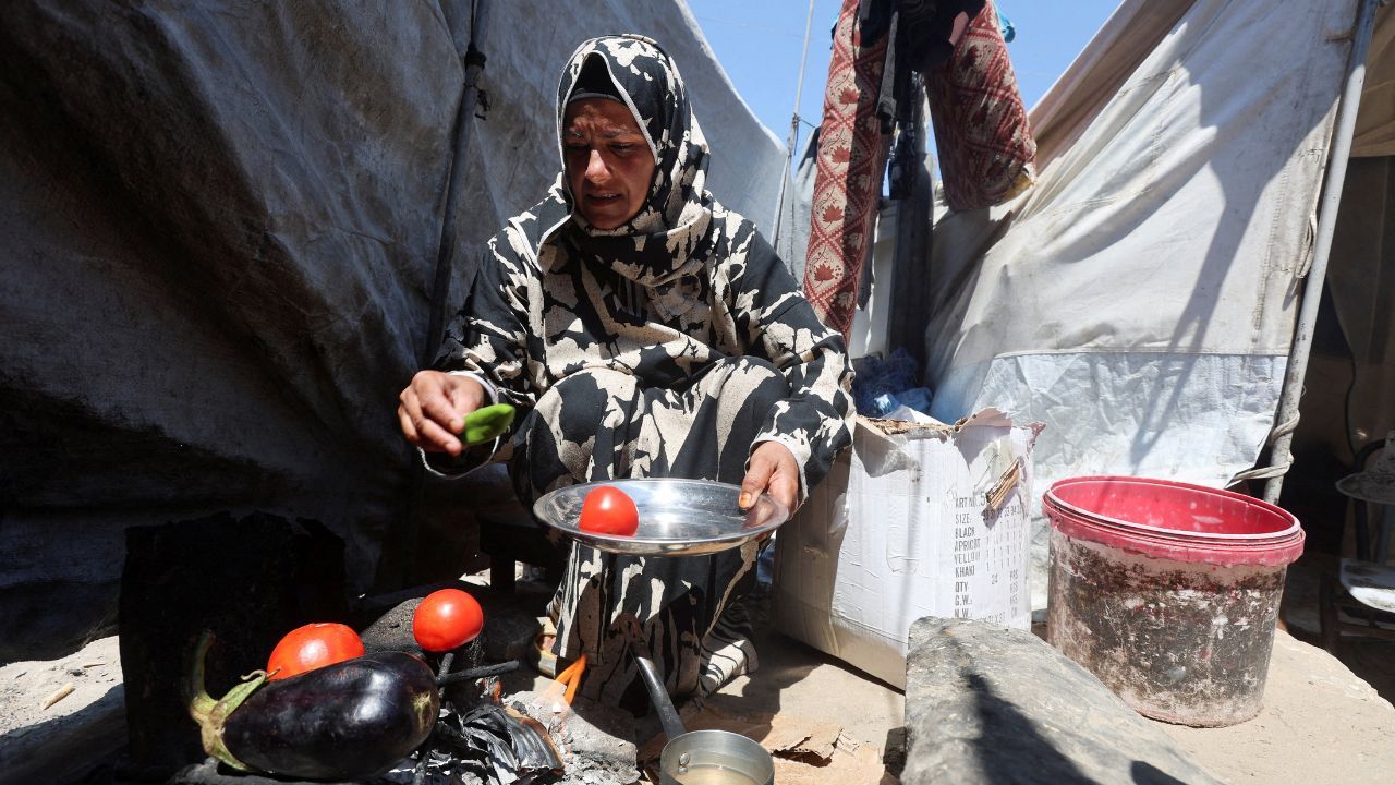 Nisreen Abu Saada, uma mulher palestina deslocada, cozinha legumes em fogo de lenha em Khan Younis, no sul da Faixa de Gaza | Foto: REUTERS/Ramadan Abed