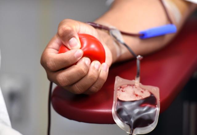 foto do braço de uma pessoa que está doando sangue. Ela aperta uma bolinha de borracha vermelha